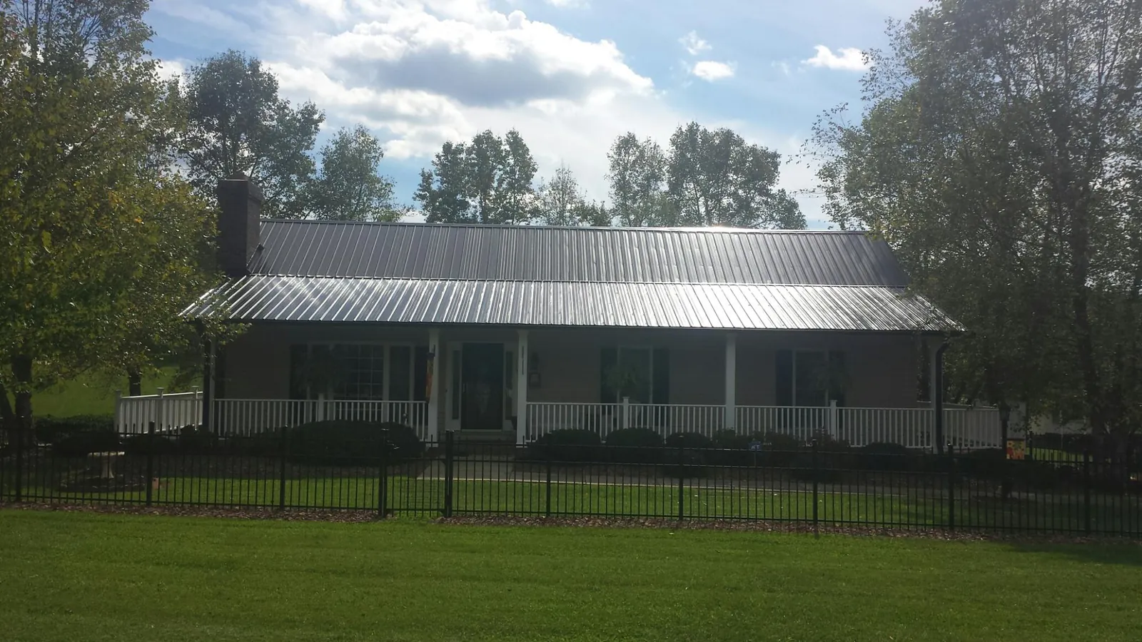 Gray metal roof on a brick ranch with a full width front porch — Gutter Guard Installation work by our crew in Foxburg