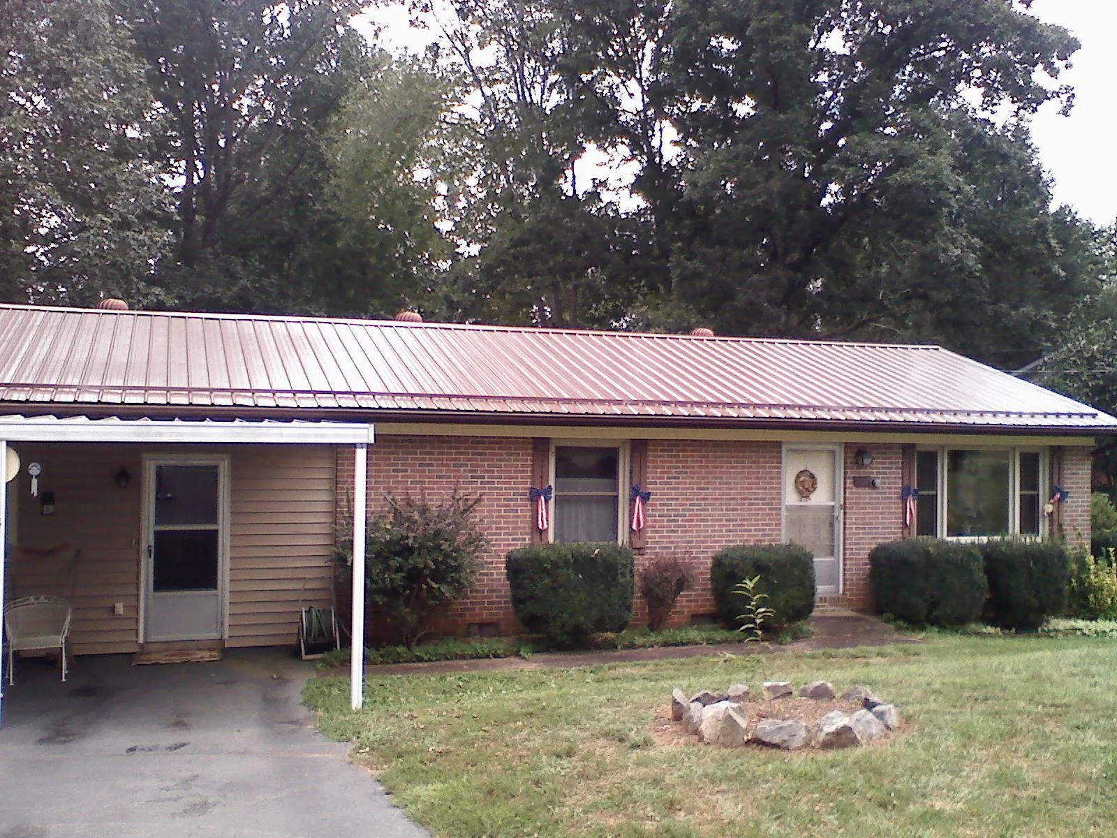 Bronze metal roof and carport on a brick ranch home — Roof Repair work by our crew in Foxburg