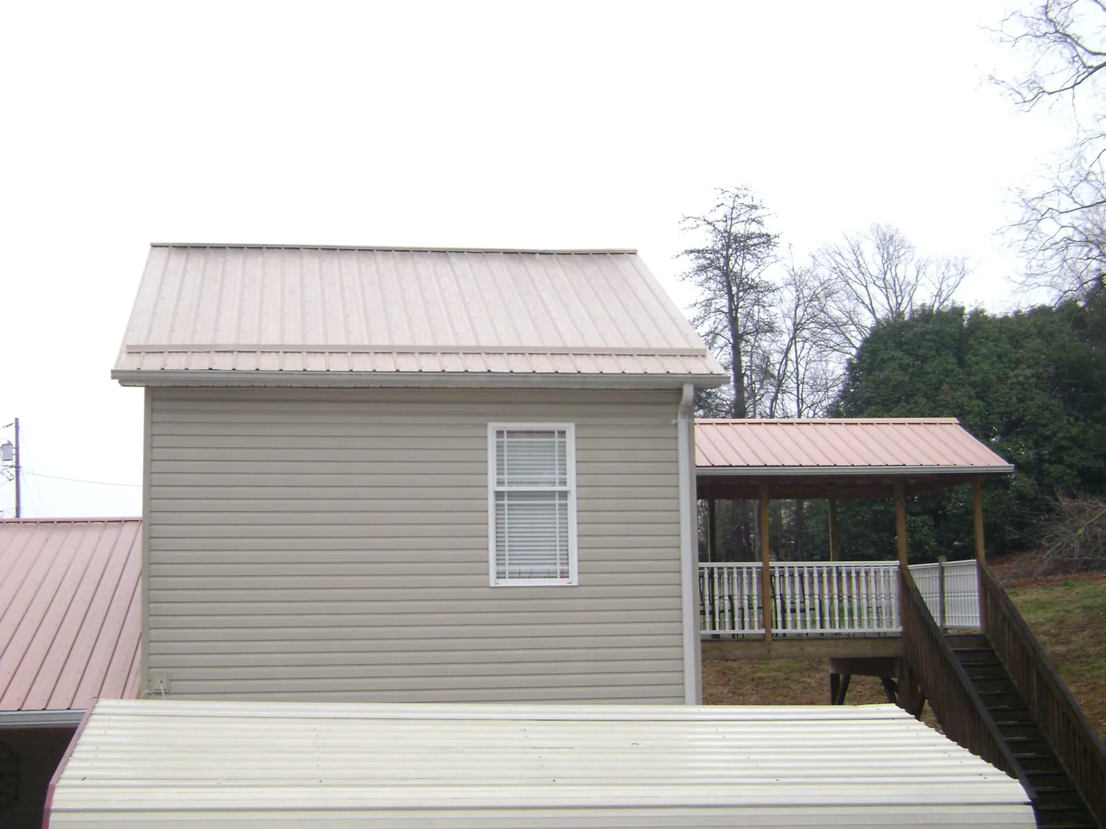 Tan metal roofs on a two story addition and attached porch, from a Roof Replacement job in Foxburg