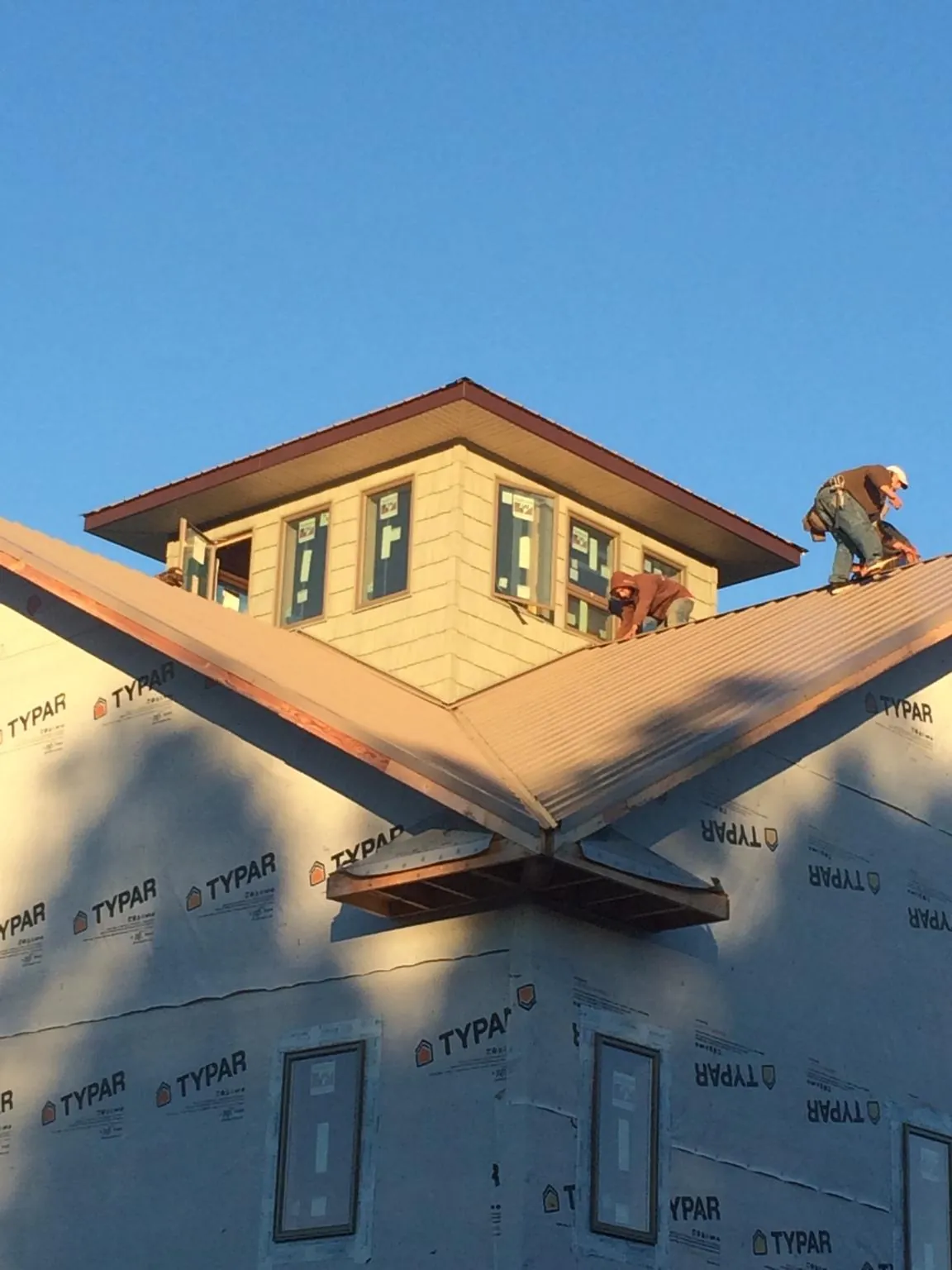 Roofers working around a rooftop cupola on a new metal roof at sunset — Roof Waterproofing in Foxburg by Roofing Brothers